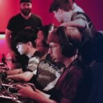 Young gamers intensely focused on competing in a youth esports league tournament under red and blue lighting.